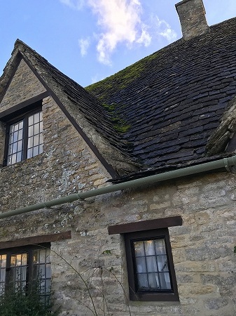 急勾配の屋根を持つはちみつ色の17世紀の石造りのコテージ