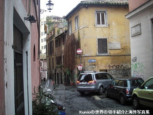 パンテオン近くのローマの裏道、坂道が多く、黄色い塀と狭い道路、所狭しと置かれた車、路上には多数のタバコの吸殻
